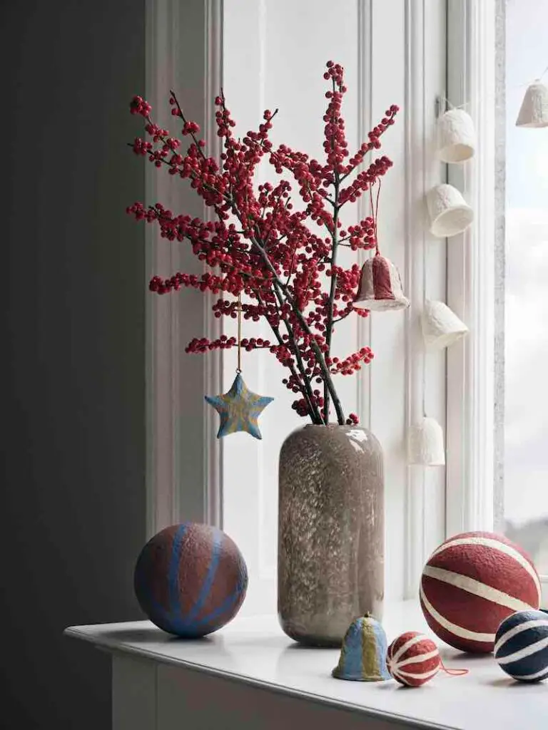 Red_Winterberry_in_a_vase_by_a_window_adorned_with _oversized_ball _decorations.